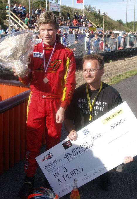 Thomas Krebs og den stolte far Klaus fremviser præmiechecken for tredjepladsen i ranglisteturneringen Dansk Super Kart.
